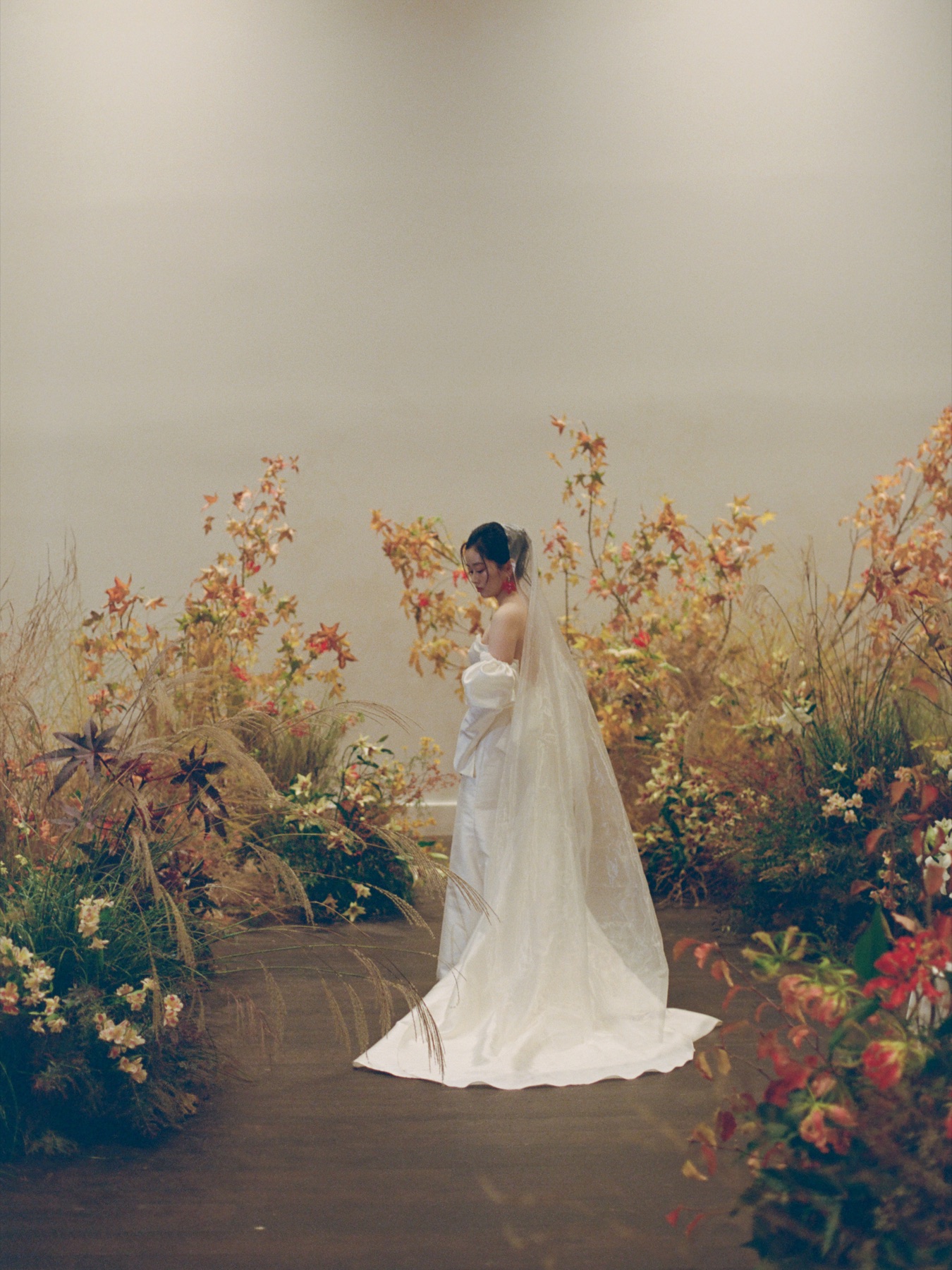 Cher standing among deep red, rust, and wild grass ceremony flowers.