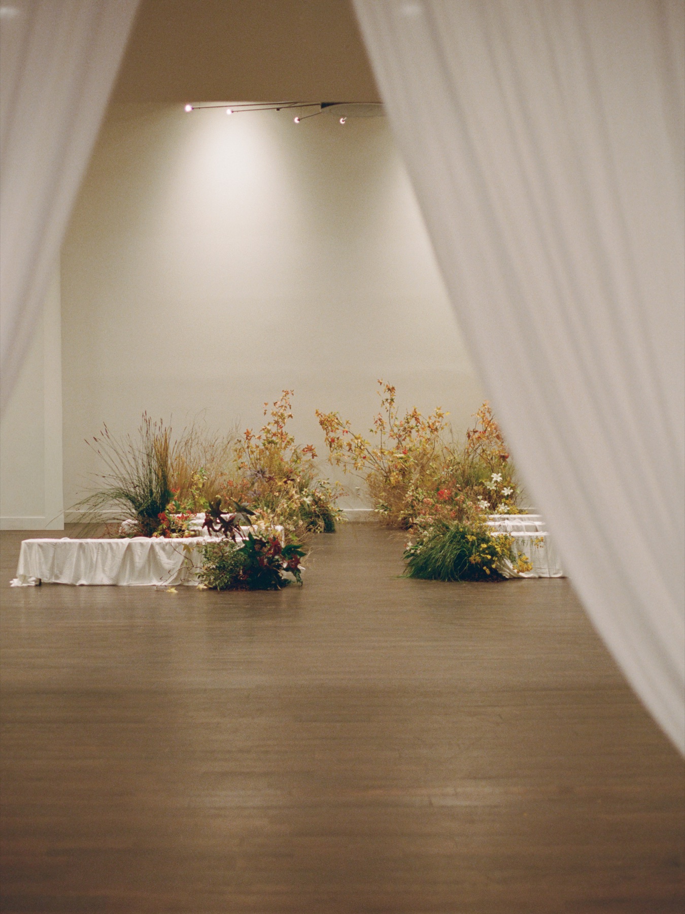 Wedding ceremony flowers in deep red, rust, and wild grass tones.